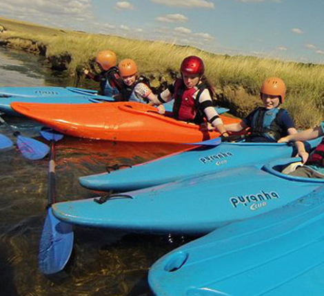 A group of children kayaking on the river, joining up their boats