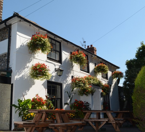 The outside of The Spotted Cow with beautiful floral hanging baskets